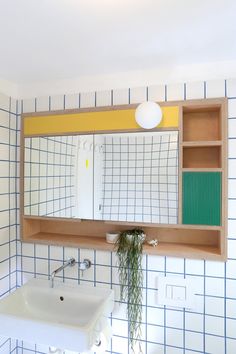 a bathroom with blue and yellow tiles on the walls, sink and mirror in it