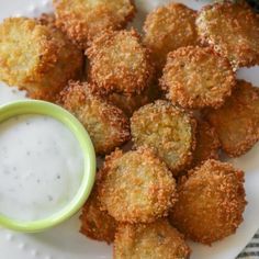 some fried food on a white plate with a small bowl of ranch dressing next to it