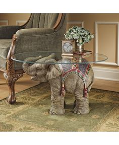 an elephant figurine stands in front of a glass table with a clock on it