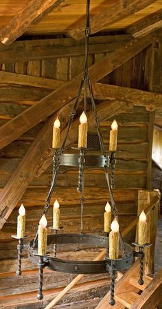 a chandelier with lit candles hanging from it's sides in an old log cabin