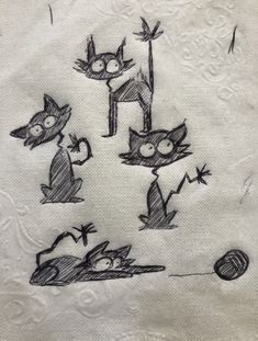 an embroidered napkin with cats on it, and balls of yarn in the air behind them