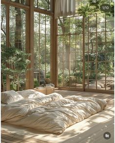 an unmade bed in a room with large windows