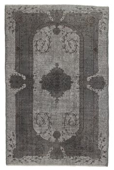 a gray rug with an ornate design on the center and sides, in grey tones