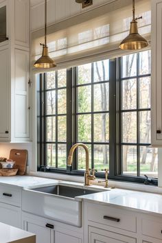 a kitchen with white cabinets and gold faucet lights hanging from the ceiling over the sink