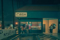 two people are standing in front of a mash store at night with the lights on