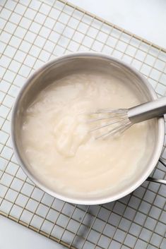 a bowl filled with cream and whisk on top of a white tiled counter