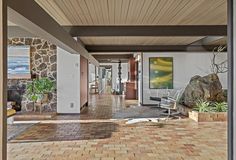 an open living room with brick flooring and stone walls, along with a painting on the wall