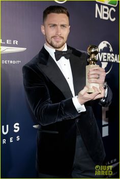 a man in a tuxedo holding an award for his role in the show