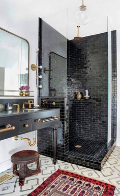 a black and white bathroom with a rug on the floor, shower stall and sink