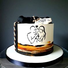 a wedding cake with an artistic design on the front and side, decorated with black ribbon