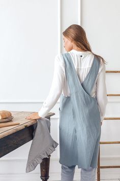 a woman standing in front of a table with a piece of cloth draped over her back