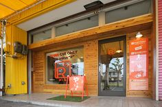 an orange and red sign sitting in front of a building next to a yellow door