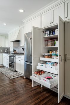 an organized kitchen with white cabinets and wood flooring is pictured in this image from the inside