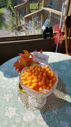 a bowl filled with oranges sitting on top of a table next to a sign