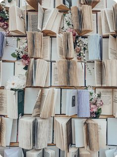 many open books are stacked on top of each other with flowers in the middle and behind them