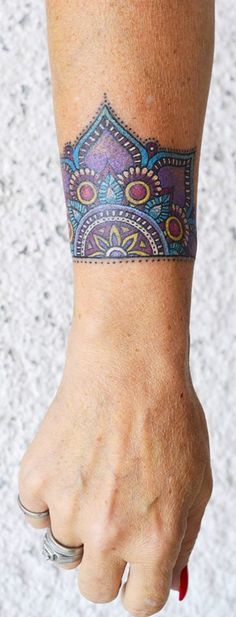 a woman's hand with a colorful tattoo on her left arm and the wrist