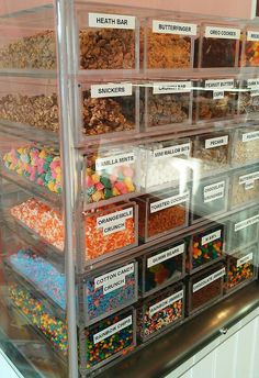 a display case filled with lots of different types of candies and cereals in plastic containers