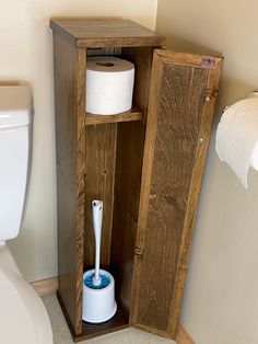 a toilet paper dispenser in a wooden cabinet next to a white toilet