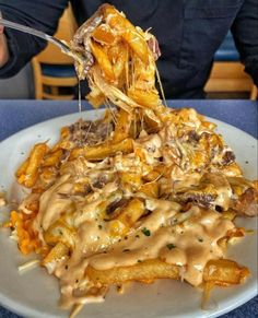 a person is eating french fries covered in gravy