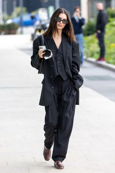 a woman walking down the street in a black suit