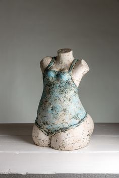 a white and blue vase sitting on top of a table next to a gray wall