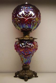 a colorful glass vase sitting on top of a white table next to a wall mounted light