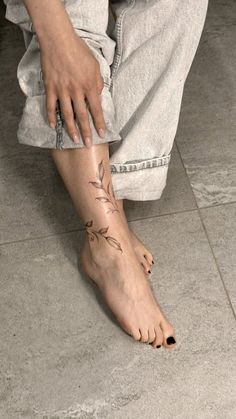 a person sitting on the floor with their foot covered in tattoos