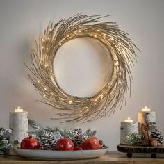 a christmas wreath with lit candles on a table next to other holiday decorations and decor items