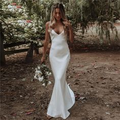 a woman in a white wedding dress is walking through the dirt with her hand on her hip