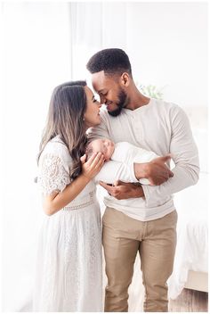 a man and woman holding a baby in their arms