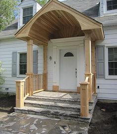 a white house with a wooden porch and steps leading up to the front door area