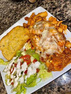 a white plate topped with food next to a salad and french fries on top of a table