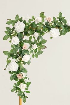 white roses and green leaves in a vase on a table with a gold base stand