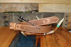 a pair of scissors sitting on top of a wooden table next to a leather belt