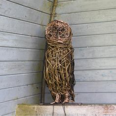 a bird made out of twigs sitting on the side of a building