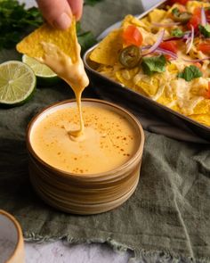 a person dipping tortilla sauce into a bowl