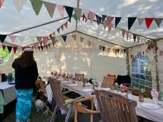 a woman standing in front of a tent with tables and chairs set up for a party