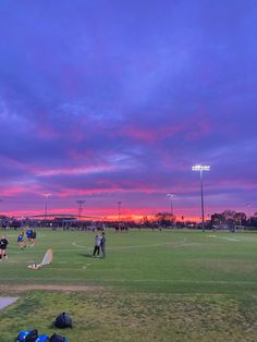 people are on the field playing baseball at sunset