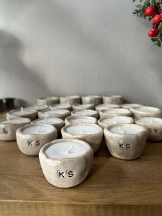 many white candles sitting on top of a wooden table