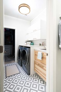 a washer and dryer in a small room with white tile on the floor