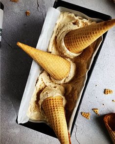 three scoops of ice cream in a black container on top of a gray table