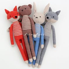 several knitted animals are arranged together on a white surface, one is grey and the other is red