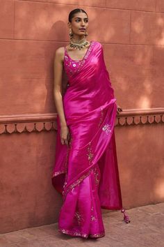 a woman in a pink sari standing next to a wall with her hand on her hip