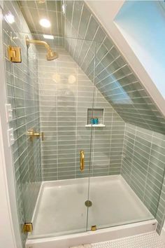 an attic bathroom with gray tile and gold fixtures