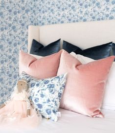 a white bed topped with pillows and a teddy bear