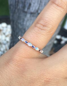 a woman's hand with a ring on it that has blue and white stones