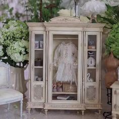 an antique china cabinet with white flowers in the background