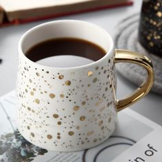 a cup of coffee sitting on top of a table next to a book and pen