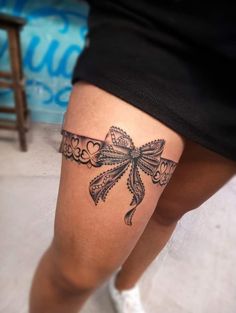 a woman's leg with a bow tattoo on the side of her thigh,