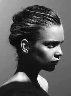 a black and white photo of a woman's face with her hair in a bun